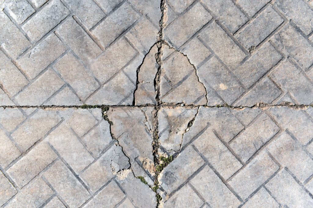 Overhead perspective of stamped concrete with significant cracks, showcasing the superiority of patio pavers in Leawood.